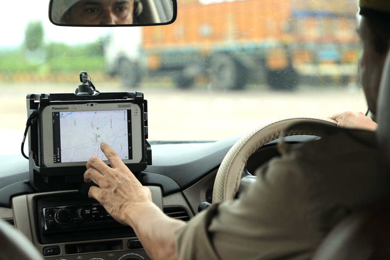 Services Police officer navigates using a digital map on a tablet inside a vehicle.